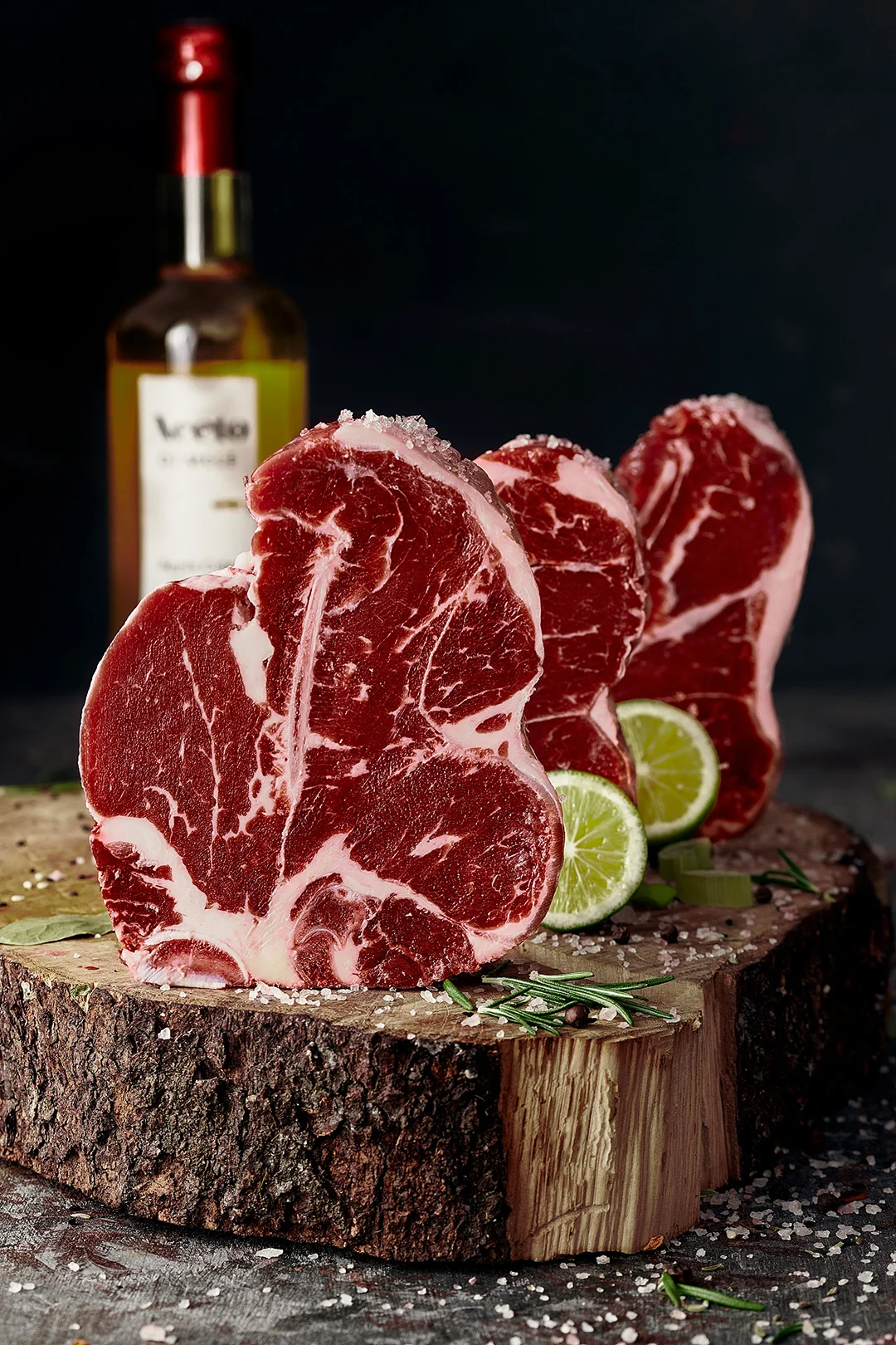 Rohes Fleisch auf einem braunen Holzschneidebrett, dekoriert mit frischen Kräutern und Gewürzen, vor einem rustikalen Hintergrund.