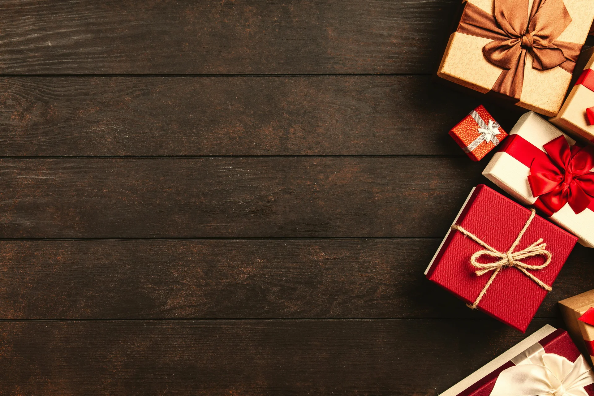 Rot und golden verpackte Geschenke auf einem Braunen Hintergrund.