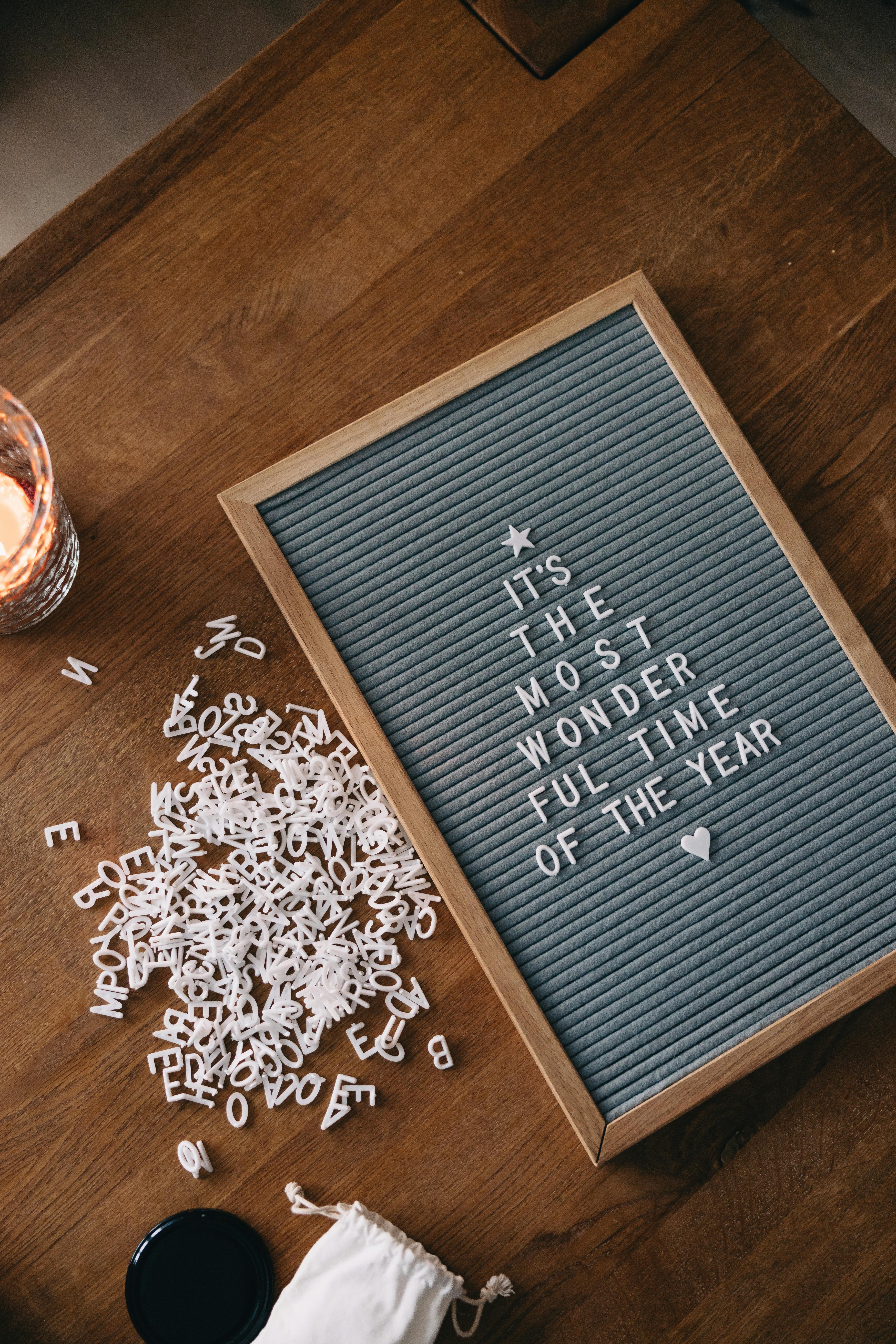 Holzbrett mit Buchstaben und Zahlen als dekorative Elemente auf einer hellen Unterlage